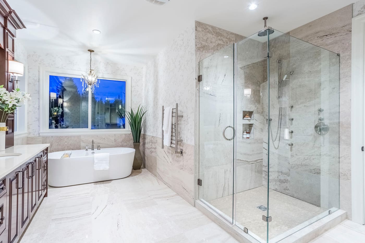 Bathroom with a freestanding tub, glass shower enclosure, and marble tile