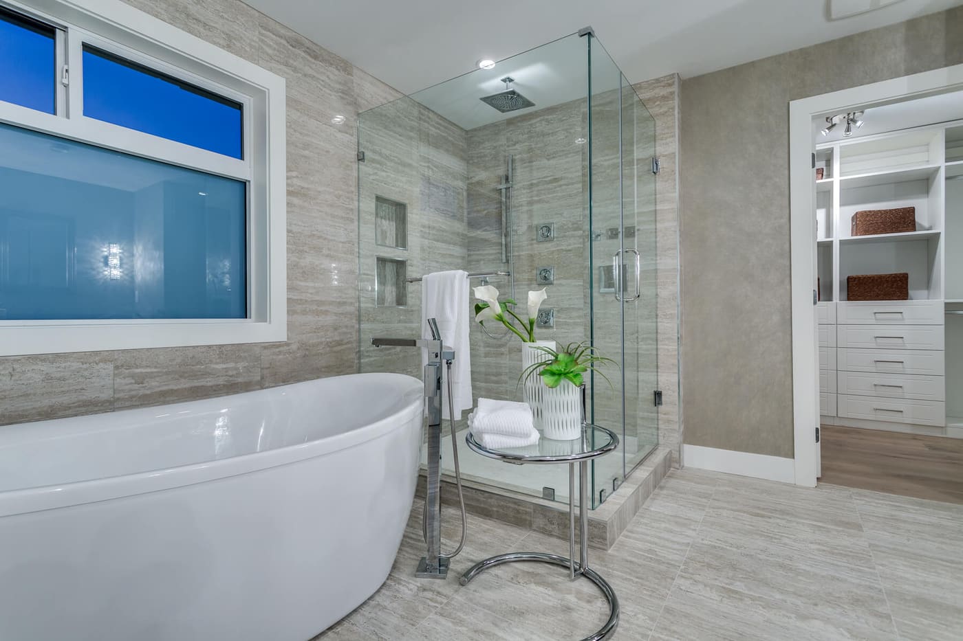 Bathroom with a freestanding tub and glass shower opening onto a walk-in closet